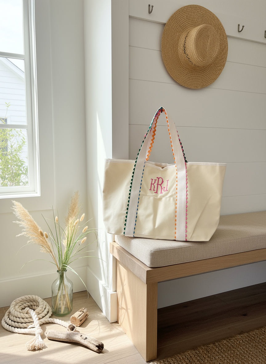 Beige tote with colorful trim and monogrammed initials on a plain background