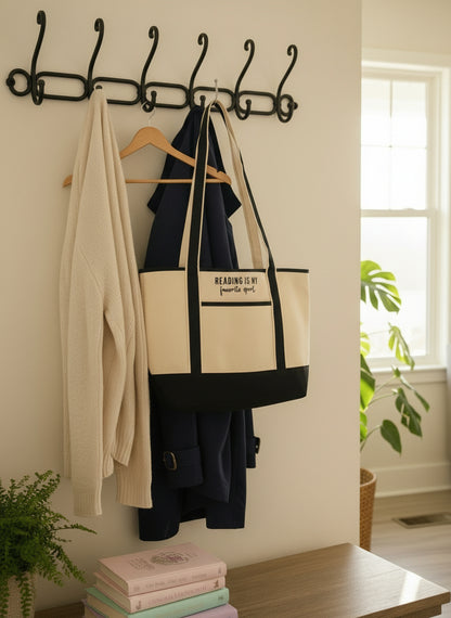 Beige tote bag with navy accents and text held by mud room hook on a white background with pastel books and greenery